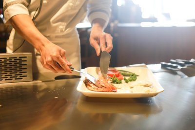 Koch oder Köchin bereitet Teller mit Essen zu